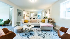 Een moderne woonkamer met een modulaire bank, voetenbankjes, een salontafel en een vloerkleed met dessin.