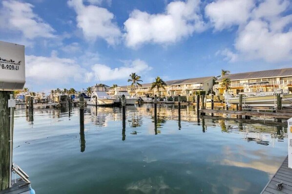 A marina with docked boats, a clear sky, and buildings with balconies.