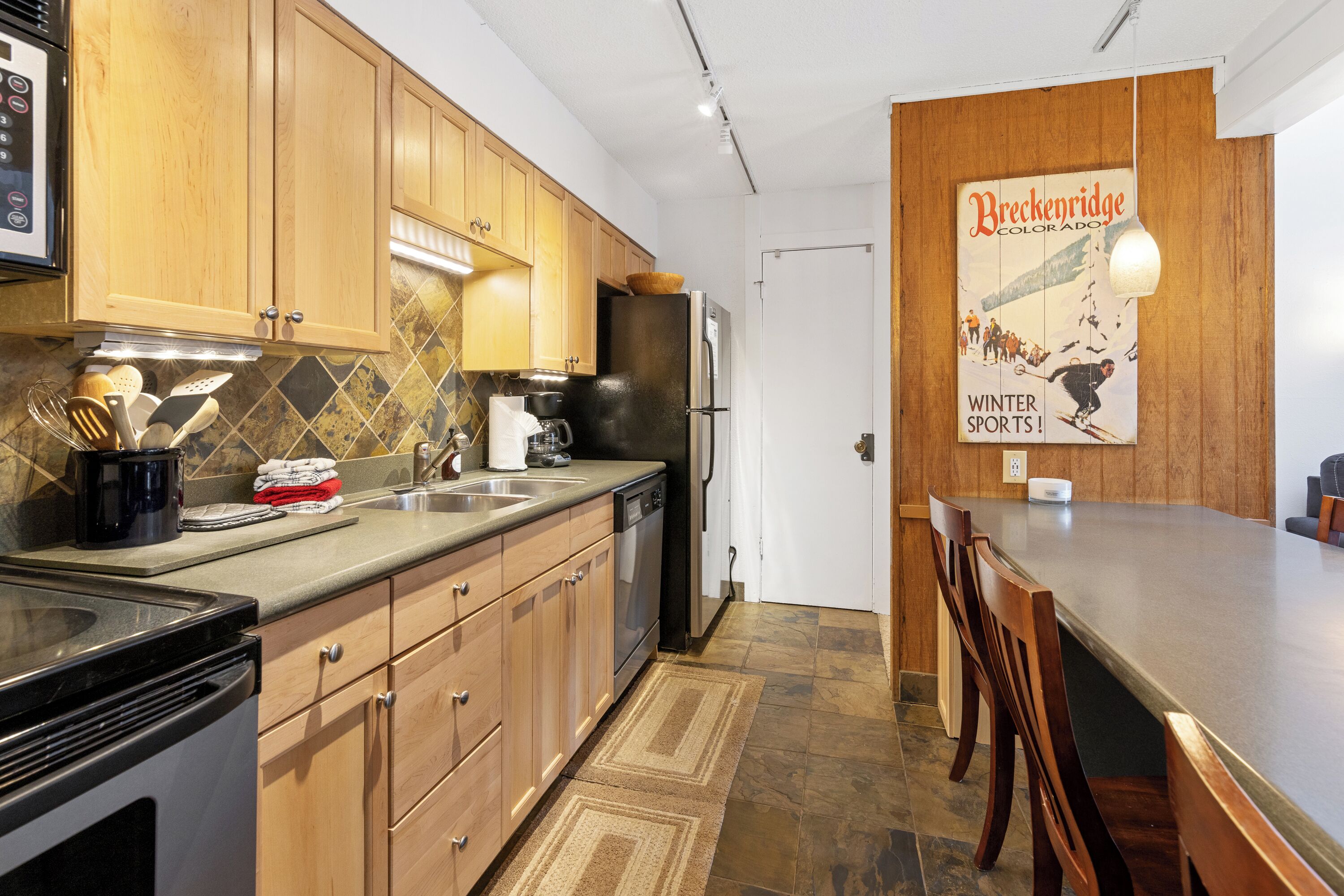 A modern kitchen with wooden cabinets, a stainless steel refrigerator, and a coffee maker.