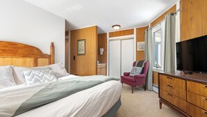 A bedroom with a bed, a chair, a TV, and a wardrobe. - BEST VALUE three bedroom in prime Peak 8 location (Breckenridge)