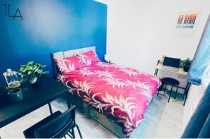 Cozy retreat with a vibrant accent wall, a comfortable bed, and a compact workspace.