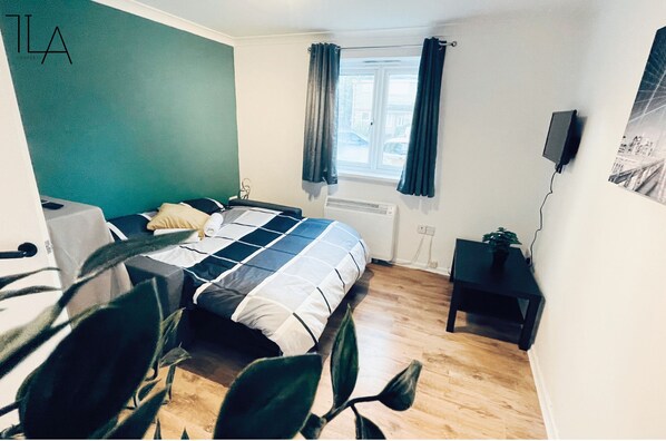 Relax in this stylish room with a comfortable bed, bedside table, and chair, plus a wall-mounted TV and radiator.