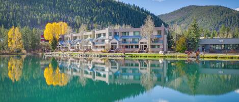 Un hôtel composé de plusieurs bâtiments situés le long d’un lac, entouré de collines boisées.
