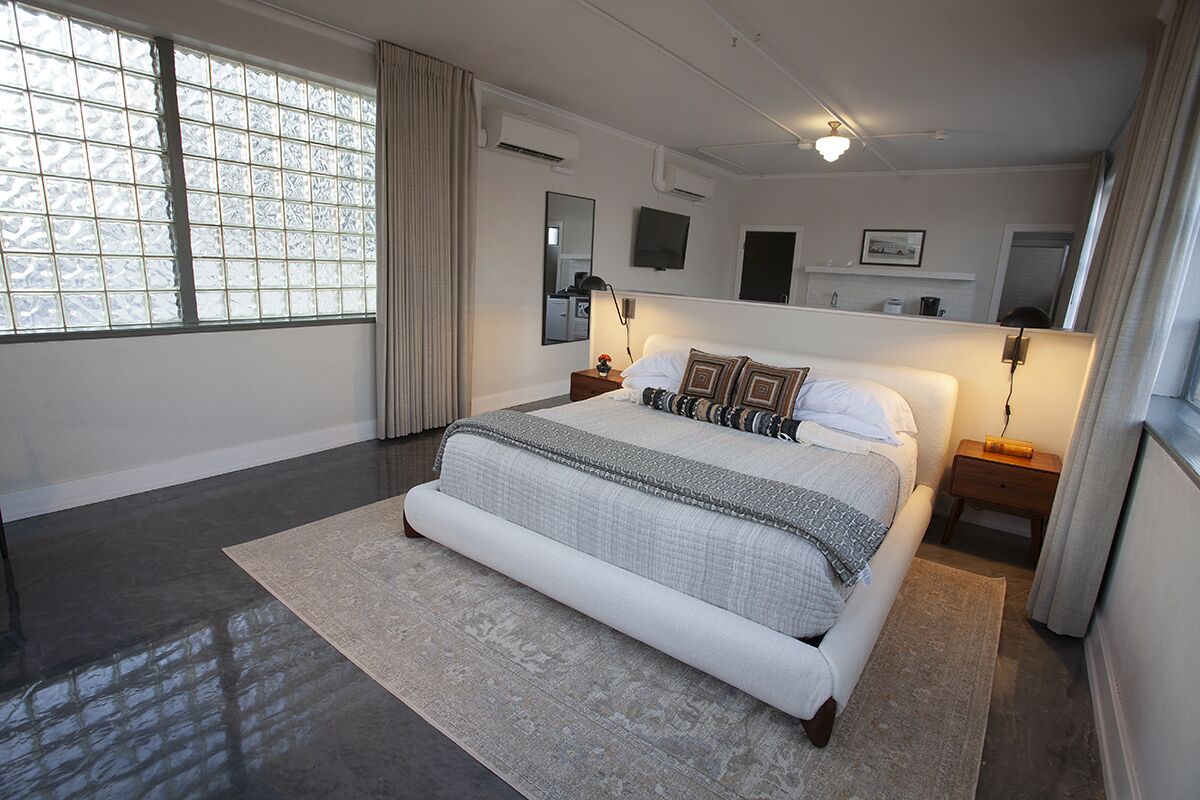 A modern bedroom with a large bed, a bedside table, a TV, and a window with curtains.