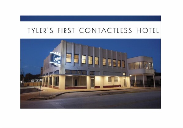 A modern hotel building with a flat facade, large windows, and a prominent sign.