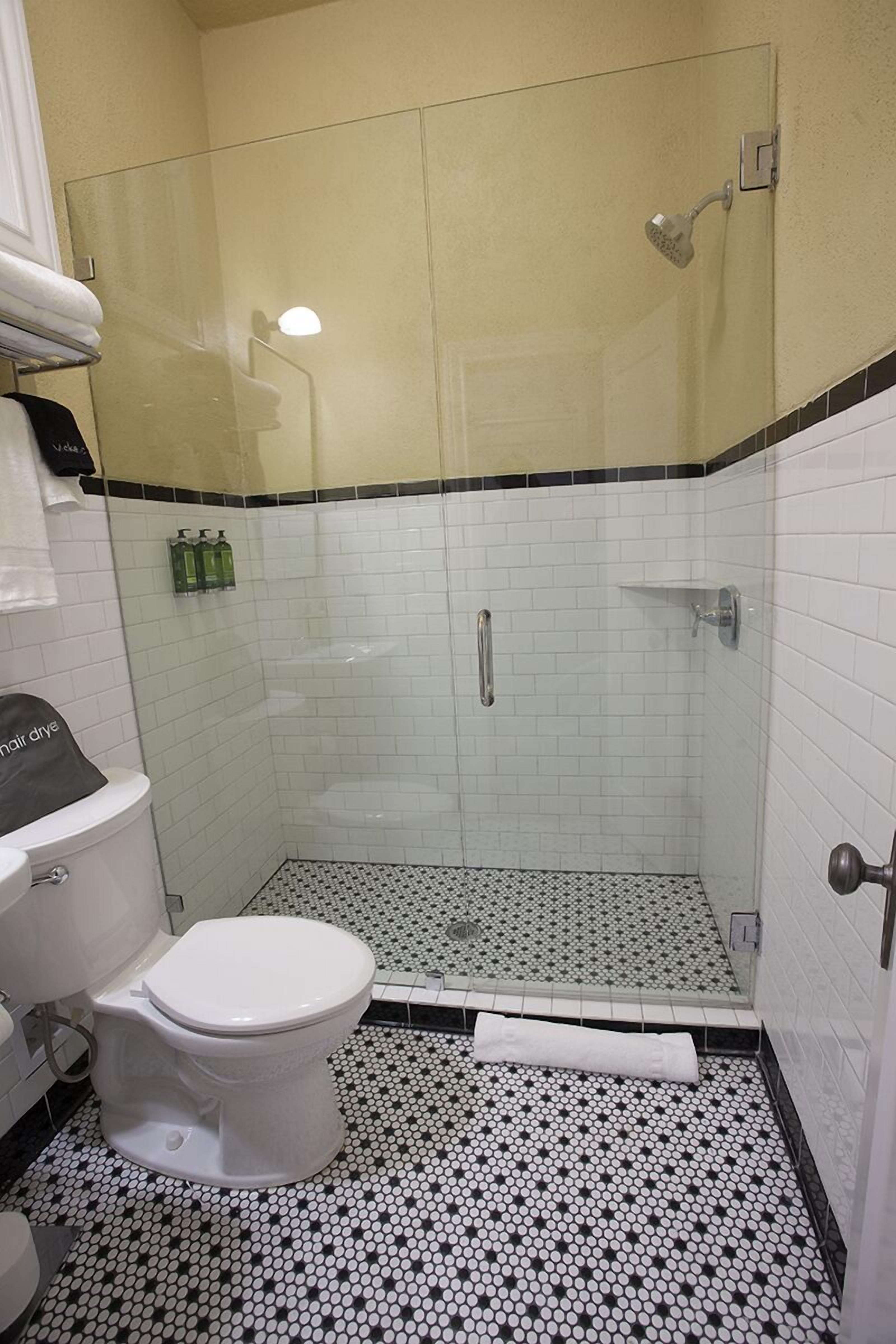 Un baño con inodoro, ducha y suelo de baldosas.