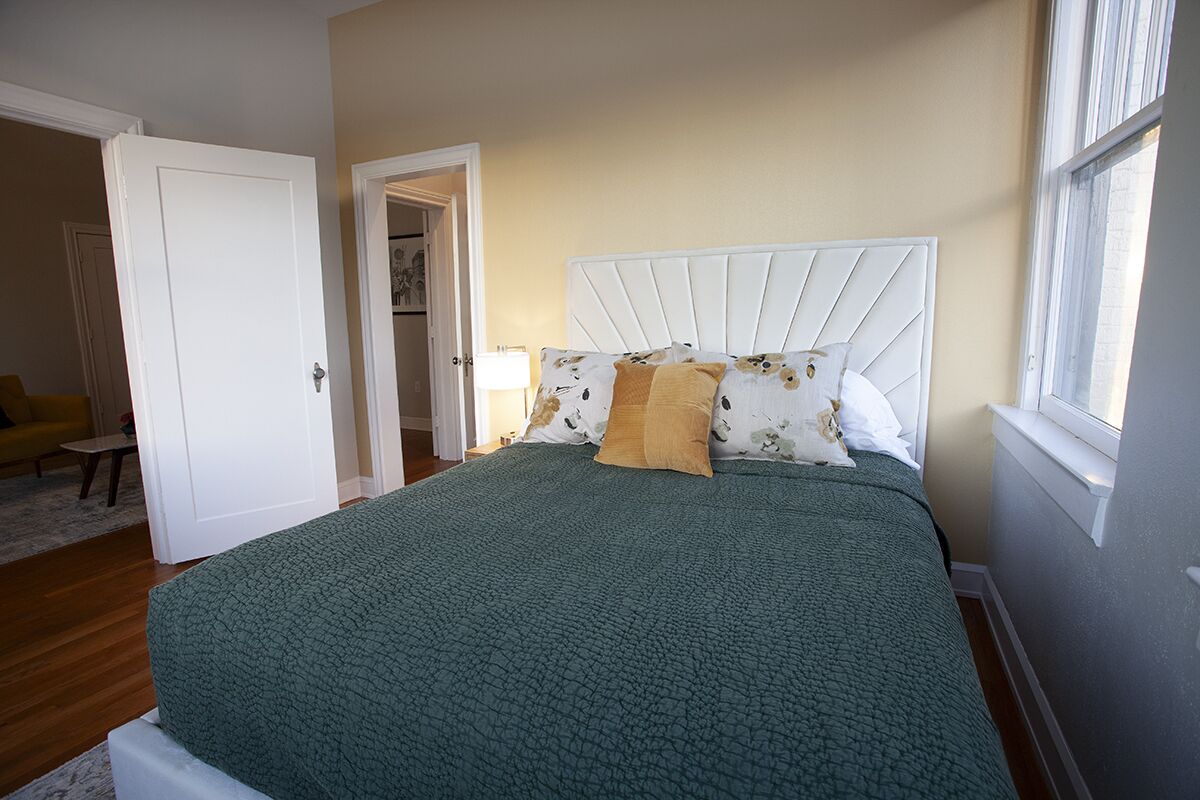 Een slaapkamer met een bed, een wit hoofdeinde en een raam.