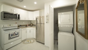 Una cocina moderna con electrodomésticos blancos, incluyendo un microondas, horno, refrigerador y lavadora.