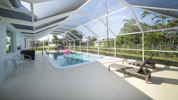 Una piscina interior con techo de cristal, rodeada de sillones de descanso y un flotador con forma de flamenco rosa.