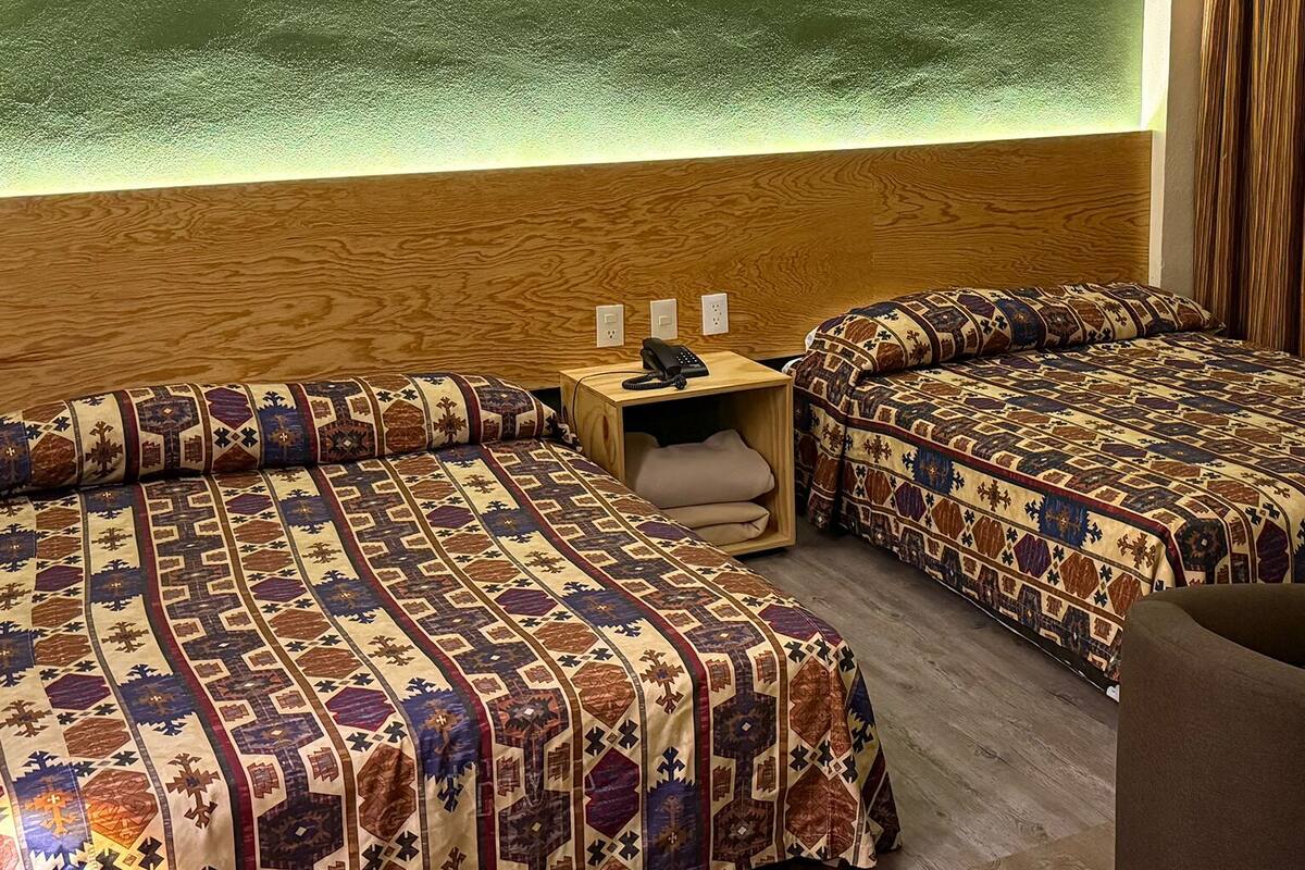 A hotel room with two beds, a small table, and a chair.