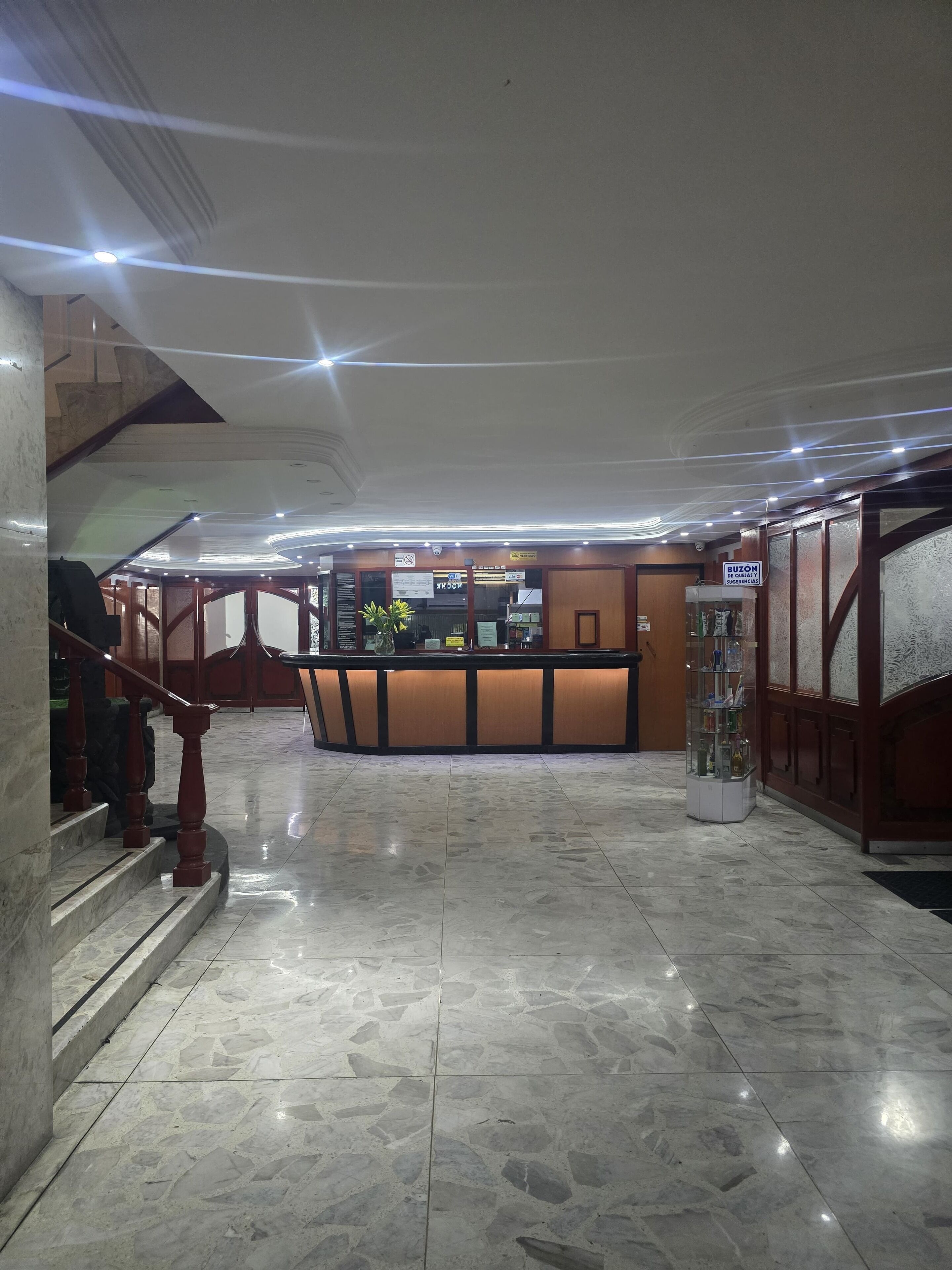 A lobby with a reception desk, a staircase, and a glass display case.