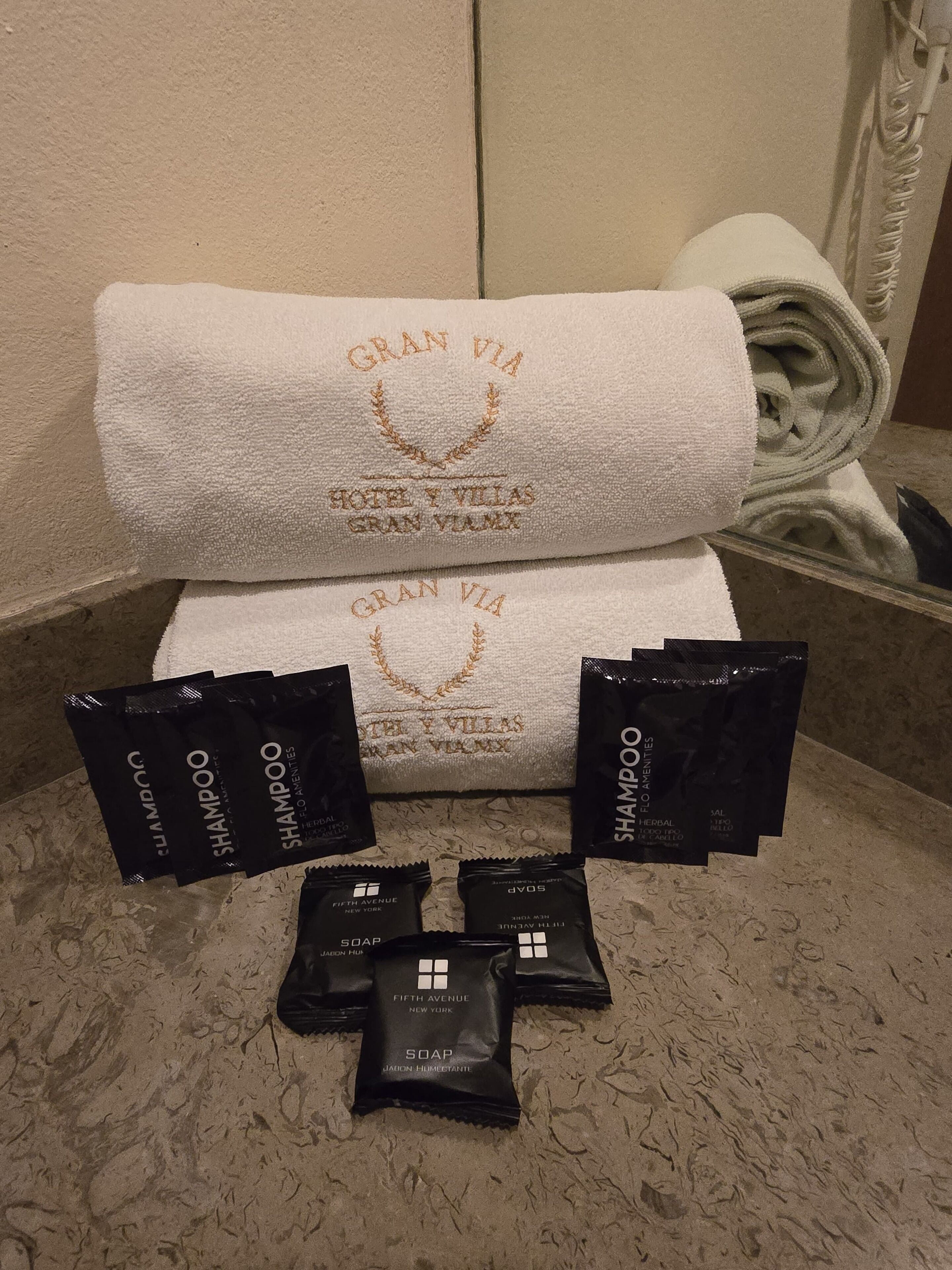 Een badkamer met een witte handdoek en diverse toiletartikelen, zoals shampoo, zeep en lotion.