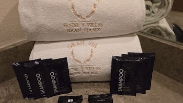 Een badkamer met een witte handdoek en diverse toiletartikelen, zoals shampoo, zeep en lotion.