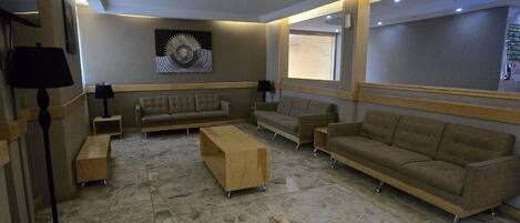 A spacious living area with a large sofa, a coffee table, and a TV mounted on the wall.