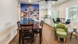 A dining area with a view of a pool and palm trees, a ceiling fan, and a green armchair. - Biltmore Boho Bungalow w/Heated Pool, Fenced Yard, AC, W/D, Fast Wifi, Smart TVs (Phoenix)