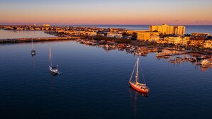 A marina with several boats, a large hotel, and a coastal town at sunset. - Coral House - Waterfront Beach Getaway, Stunning Sunsets, 9 min walk to beach! (Wrightsville Beach)