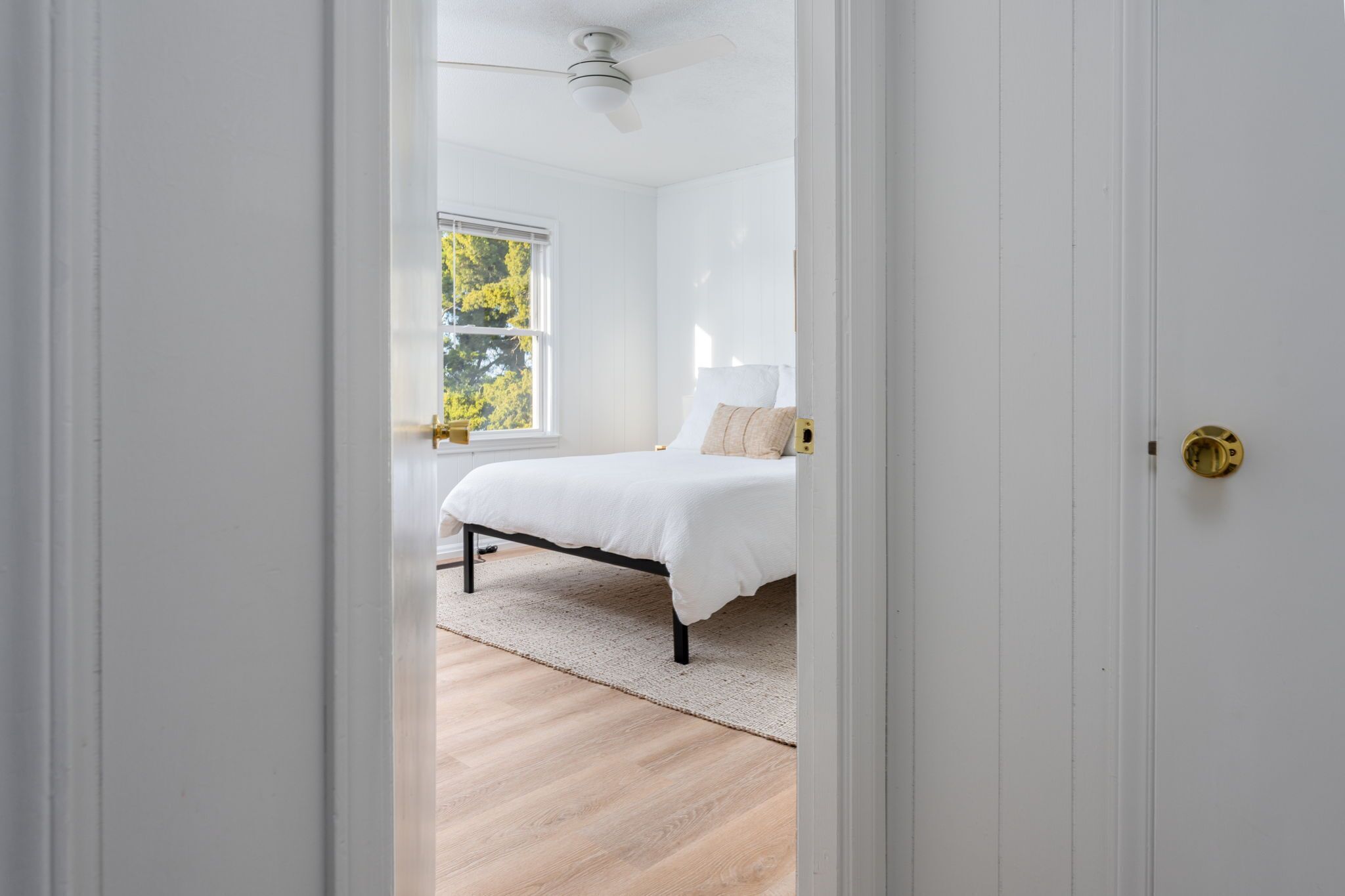 Een slaapkamer met een bed, een raam en een plafondventilator.