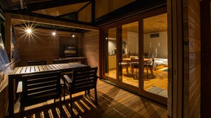 Eine Holzhütte mit Essbereich, Grill und einer Glasschiebetür, die zum Schlafzimmer führt.