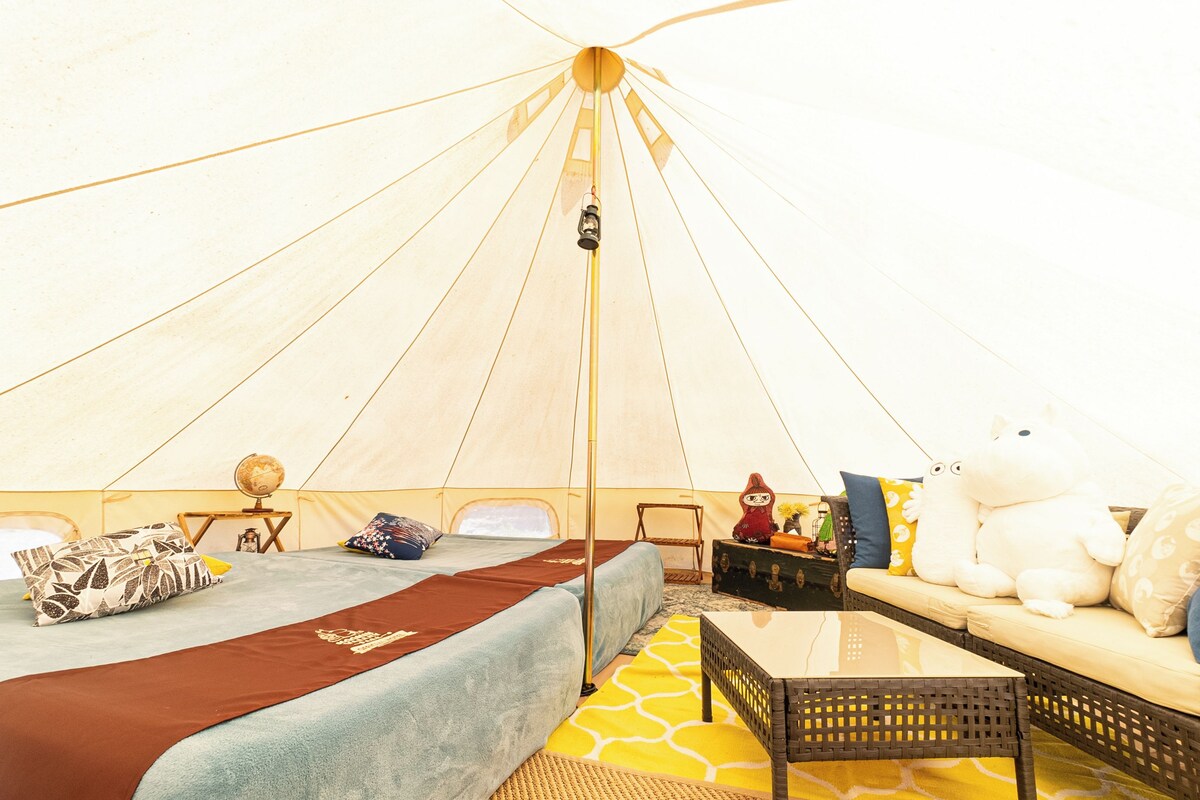 A tent with a bed, a sofa, a table, and a globe.