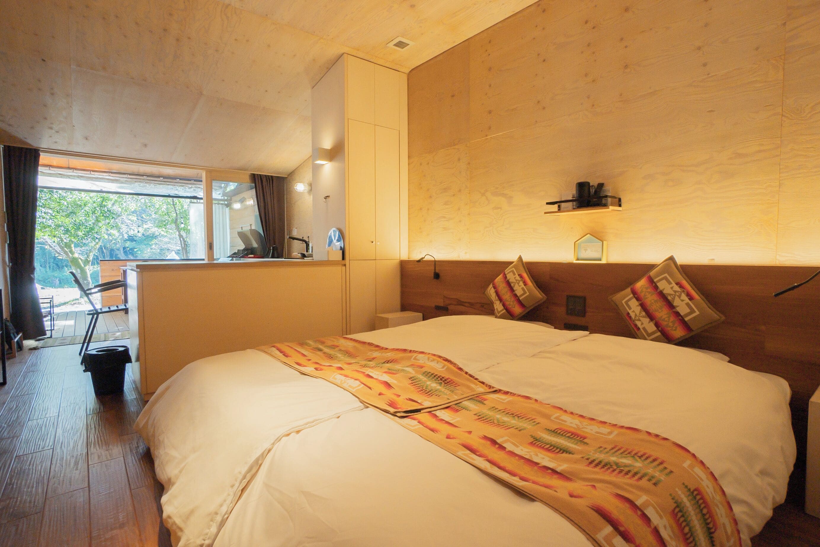 Une chambre d’hôtel avec un grand lit, un plafond en bois et un petit bureau avec une chaise.