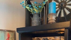 A coffee station with a coffee machine, two mugs, a bottle of Torani syrup, and a decorative rooster painting. - The Outside Inn at The Tipsy Goat Ranch (Lakeside)