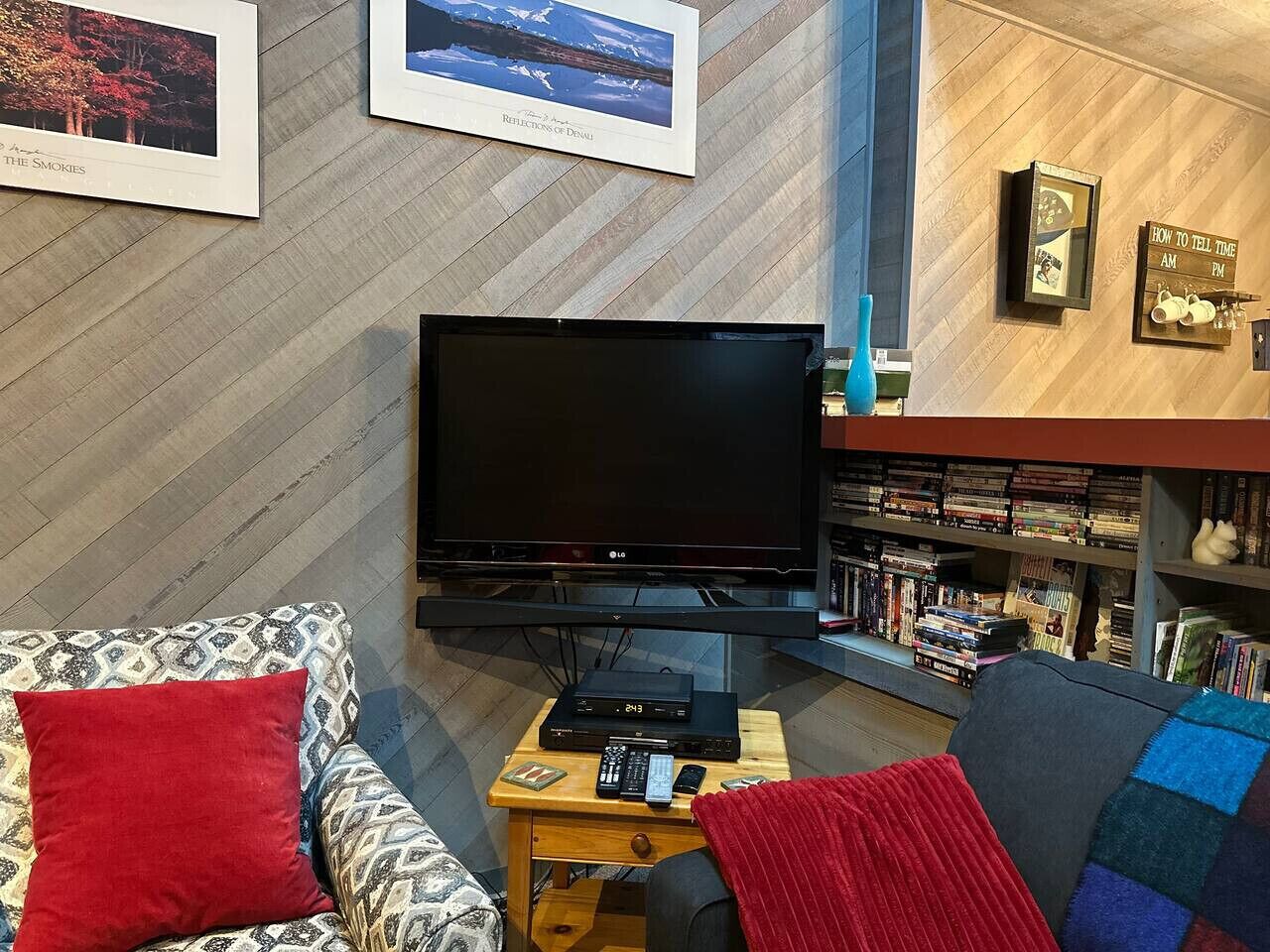 A living room with a flat-screen TV, a bookshelf, and a fireplace.