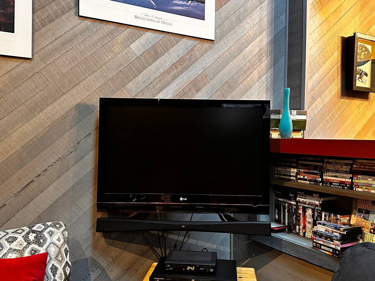 Una sala de estar con un televisor de pantalla plana, una estantería y una pared con diseño.