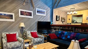 A cozy living room with patterned armchairs, a sofa, a coffee table, and a bookshelf. - Apex Mountain ~ The Powderhorn (Hedley)