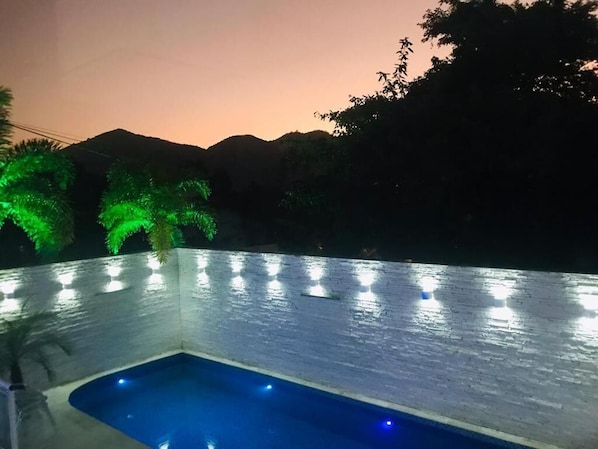 Una piscina con pared texturizada y una serie de luces a lo largo del borde.