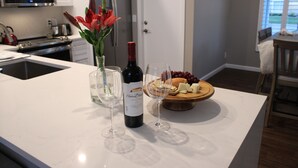A kitchen island with a wine bottle, glasses, and a fruit platter. - Abacoa/Alton area Heated Pool/Spa Luxury 4Bed Home (Jupiter)