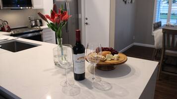 A kitchen island with a wine bottle, glasses, and a fruit platter.