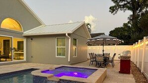 A backyard with a swimming pool, a hot tub, a barbecue grill, and a dining area with an umbrella. - Abacoa/Alton area Heated Pool/Spa Luxury 4Bed Home (Jupiter)