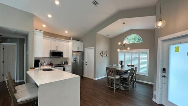 A spacious kitchen with white cabinets, a central island, and a dining area with a wooden table and chairs. - Abacoa/Alton area Heated Pool/Spa Luxury 4Bed Home (Jupiter)