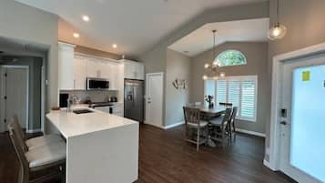 A spacious kitchen with white cabinets, a central island, and a dining area with a wooden table and chairs.