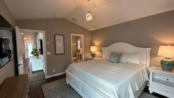A bedroom with a large bed, two bedside tables, a nightstand, a dresser, and a ceiling light fixture.