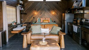A cozy cabin interior with a loft bed, a dining area, and a kitchen. - Hidden Mountaintop Getaway (Scottsboro)