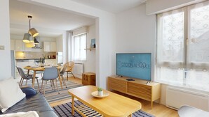 A modern living room with a sofa, dining table, and TV. - Elegance, appartement 6 pers.+ parking (Colmar)