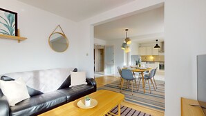A modern living room with a leather sofa, a wooden coffee table, and a dining area with a table and chairs. - Elegance, appartement 6 pers.+ parking (Colmar)