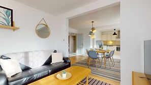 A modern living room with a leather sofa, a wooden coffee table, and a dining area with a table and chairs.