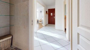A hallway with a tiled floor, a wicker basket, and a wooden door. - Elegance, appartement 6 pers.+ parking (Colmar)