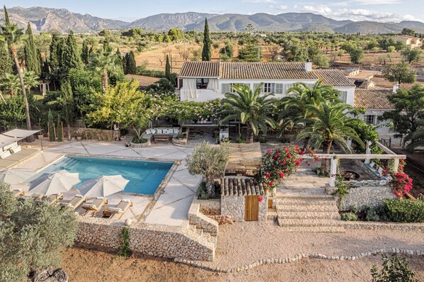 A villa with a swimming pool, surrounded by lush greenery and mountains in the background. - Can Lull, Casa Familiar Totalmente Renovada y Rodeada de Olivos (Marratxi)