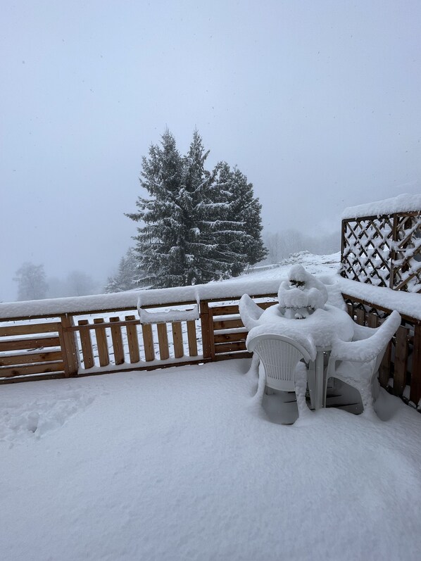 A snow-covered outdoor area with a wooden fence and a snow-covered chair.