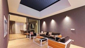 Un salon moderne comprenant un ensemble de canapés, une table basse et une cloison en verre donnant sur un espace repas.