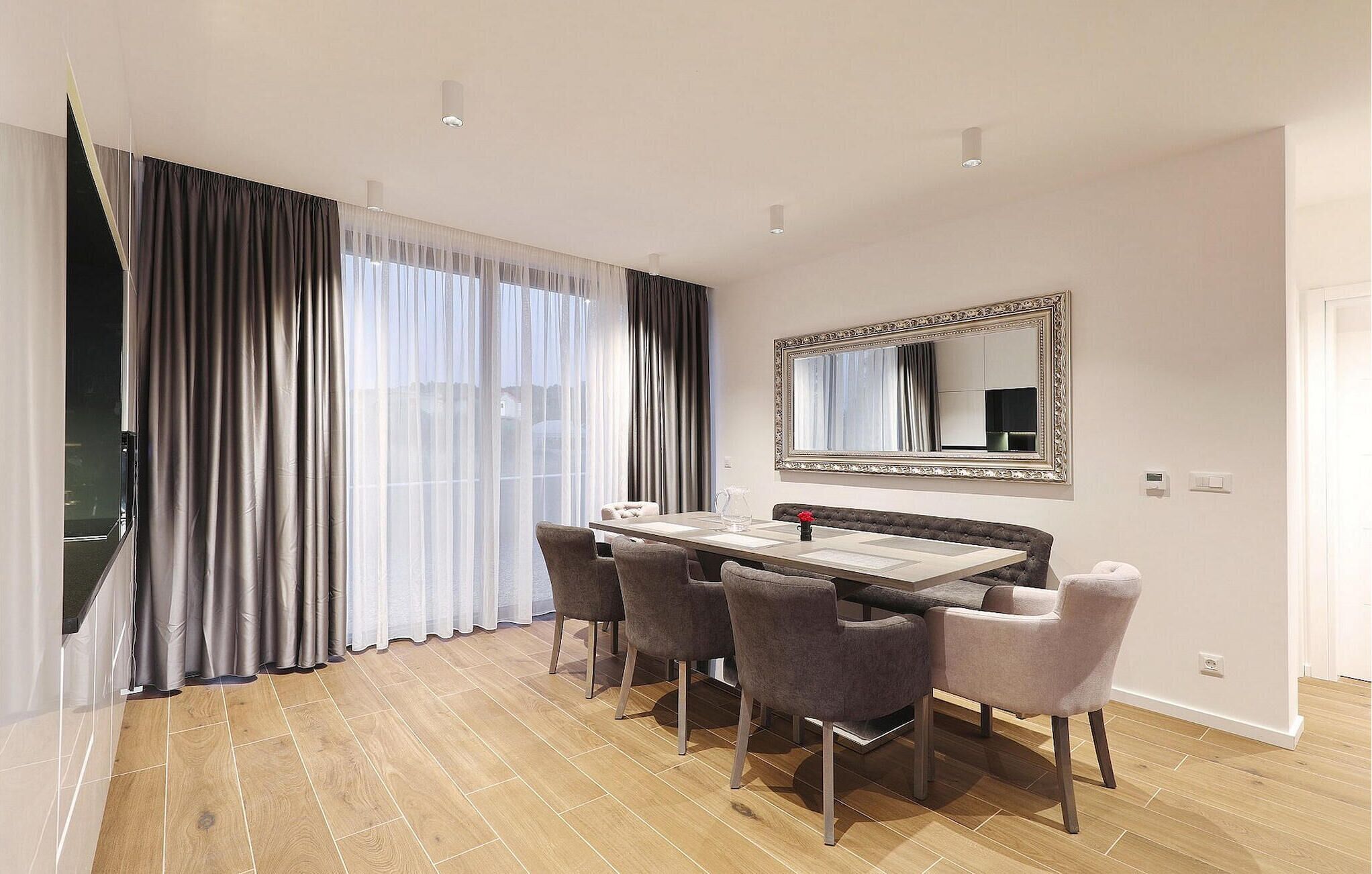 A modern dining area with a wooden floor, a rectangular table, and four chairs.