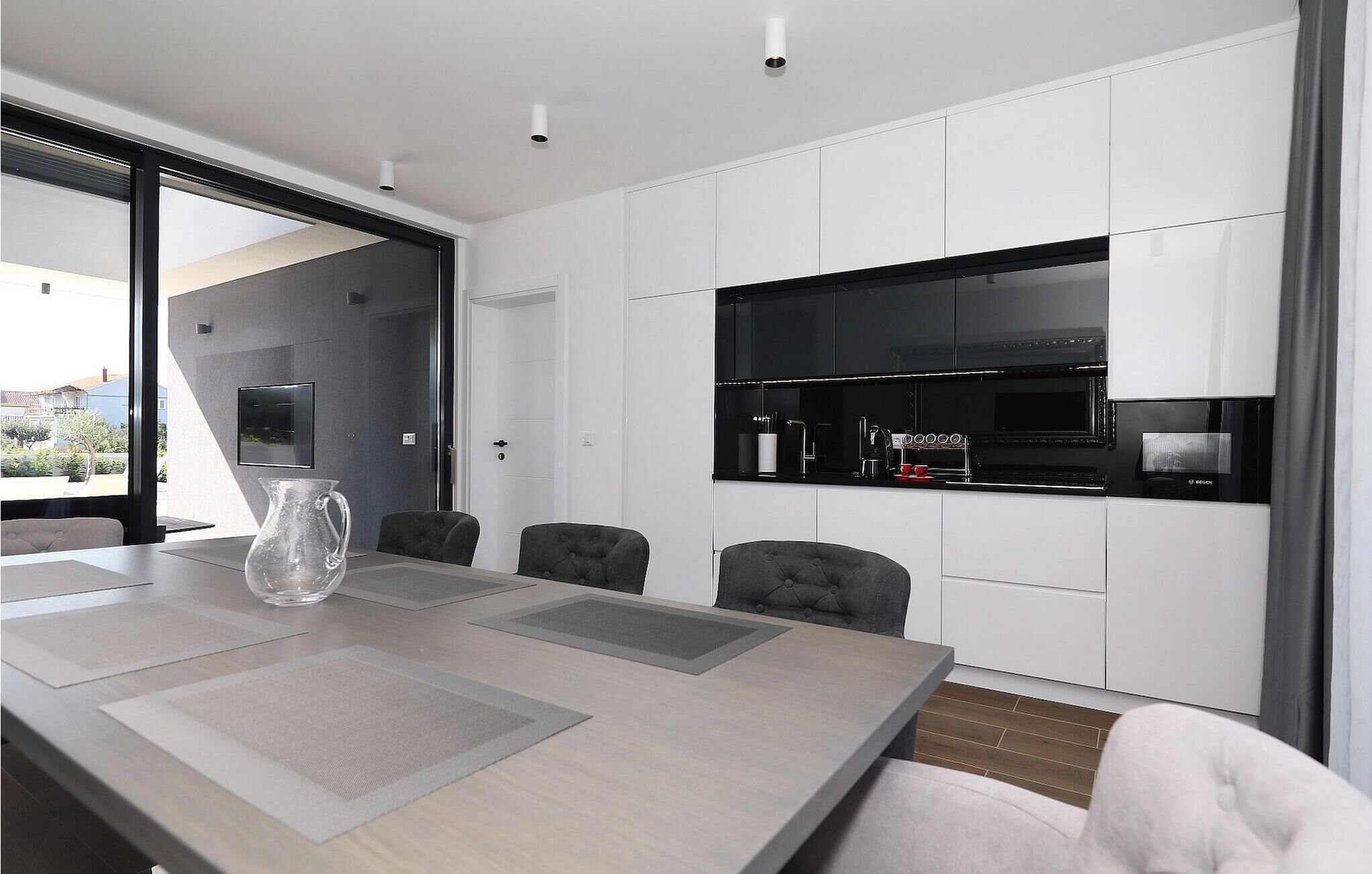 A modern kitchen with white cabinets, a black stove, and a Bosch microwave.