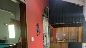 A room with a pool table, a sofa, a decorative wall piece, and a refrigerator.