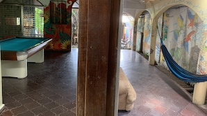 A pool table, a hammock, and a mural with colorful birds.