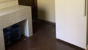 A small kitchen with a microwave, refrigerator, and tiled backsplash.