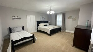 Une chambre avec deux lits, une commode et un lustre.