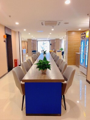 A conference room with a long table, chairs, a potted plant, and a vending machine. - 7 Days Premium (Beijing)